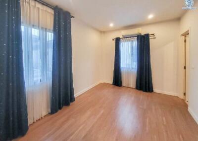 Spacious bedroom with wooden flooring and large windows