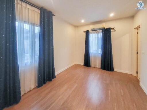 Spacious bedroom with wooden flooring and large windows