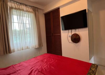 Bedroom with large windows, wooden closet, and mounted TV