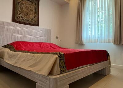 Modern bedroom with wooden bedframe and red bedspread