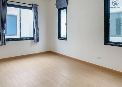 Bright and empty bedroom with wooden floors and large windows