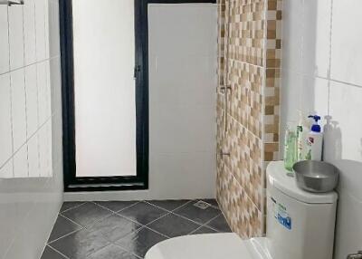 Modern bathroom with tiled walls and floor, glass shower door, toilet, and sink