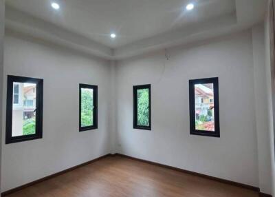 Spacious bedroom with wooden flooring and multiple windows