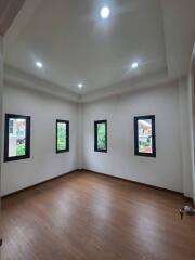 Spacious bedroom with wooden flooring and multiple windows