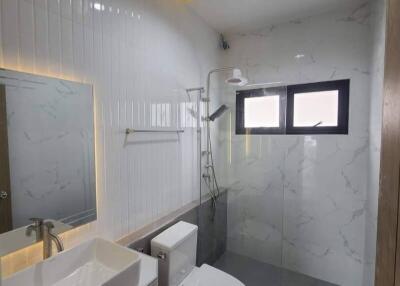 Modern bathroom with white ceramic wall tiles, sink, toilet, and walk-in shower