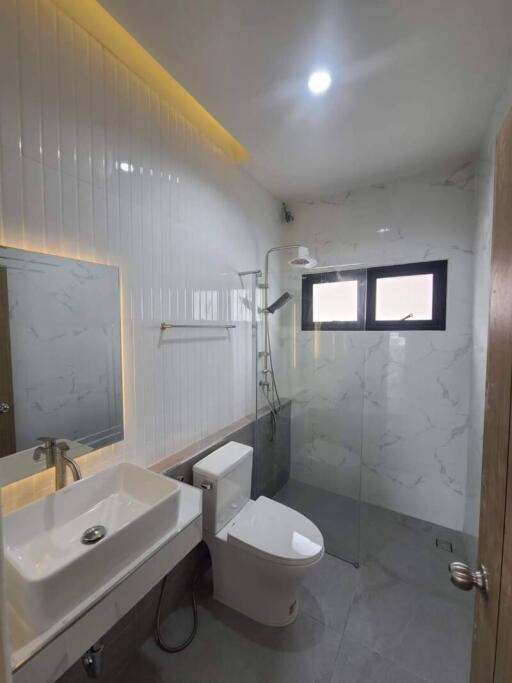 Modern bathroom with white ceramic wall tiles, sink, toilet, and walk-in shower