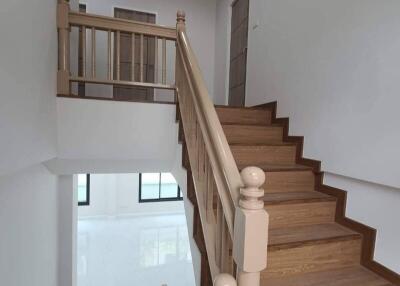 Interior view of a staircase with wooden steps and white walls.