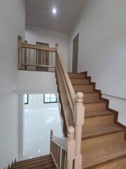 Interior view of a staircase with wooden steps and white walls.