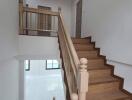 Interior view of a staircase with wooden steps and white walls.