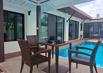 Outdoor seating area next to a swimming pool and house exterior