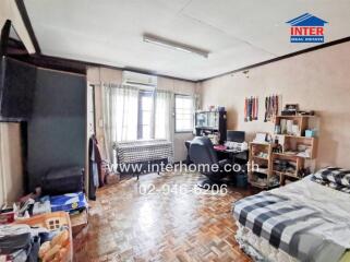 Bedroom with wooden flooring, window with curtains, desk, chair, and bed