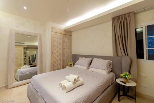 Modern bedroom with double bed, neatly made with pillows and towels, and warm lighting