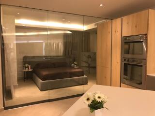 Modern bedroom with glass wall and adjacent kitchen area