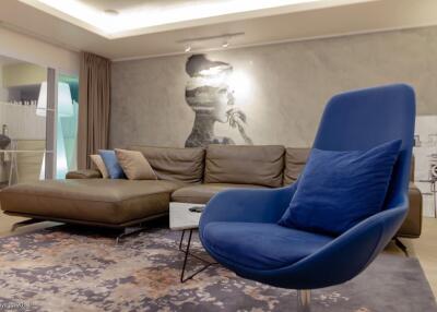 Modern living room with mural, blue armchair, and brown sectional sofa