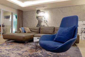 Modern living room with mural, blue armchair, and brown sectional sofa