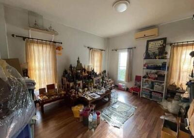 Bedroom with wooden flooring, multiple windows, and personal decorations