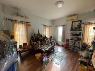 Bedroom with wooden flooring, multiple windows, and personal decorations