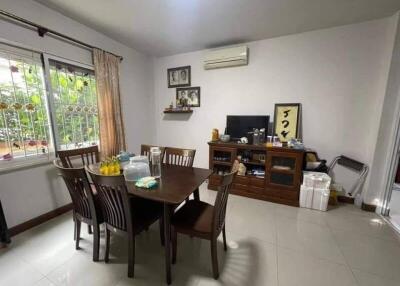 Dining room with wooden table and chairs, decorated wall with photos, air conditioner, and TV.