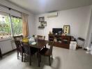 Dining room with wooden table and chairs, decorated wall with photos, air conditioner, and TV.