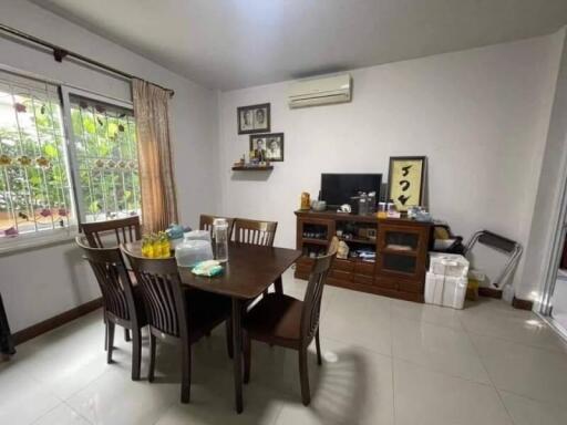 Dining room with wooden table and chairs, decorated wall with photos, air conditioner, and TV.