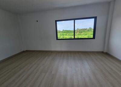 Spacious empty bedroom with large window overlooking greenery