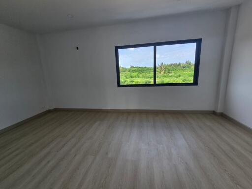 Spacious empty bedroom with large window overlooking greenery