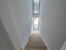 Bright staircase with wooden steps and a skylight