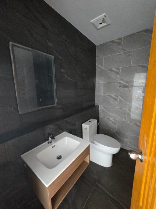 Modern bathroom with sink, mirror, toilet, and contemporary tiling