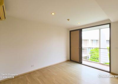 Empty room with wooden floor, large window, and door to balcony