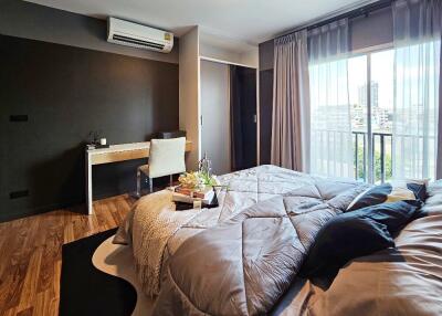 Modern bedroom with a large bed, study desk, and window view