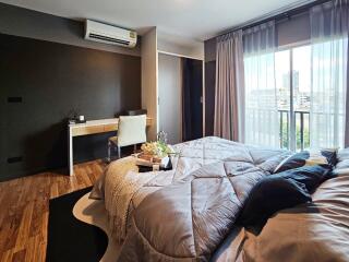 Modern bedroom with a large bed, study desk, and window view