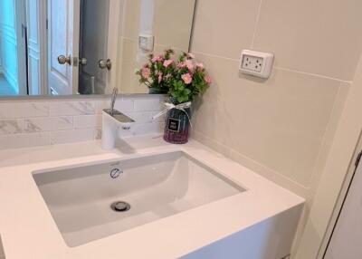 Modern bathroom sink area with mirror and flowers