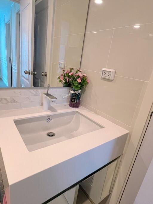 Modern bathroom sink area with mirror and flowers