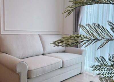 A cozy corner with a white sofa and large window