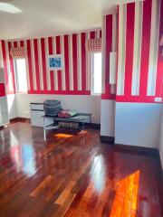 Bedroom with hardwood floors and red striped wallpaper