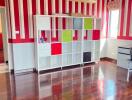 A brightly painted bedroom with striped walls, wooden flooring, and a colorful storage unit.