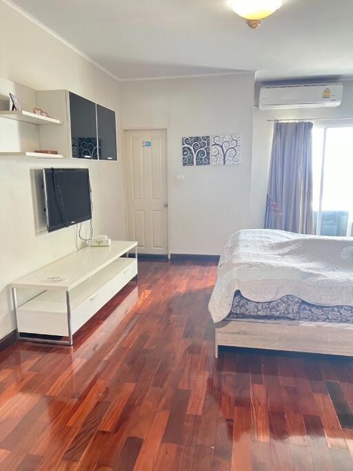 Modern bedroom with hardwood floors, mounted TV, and air conditioning