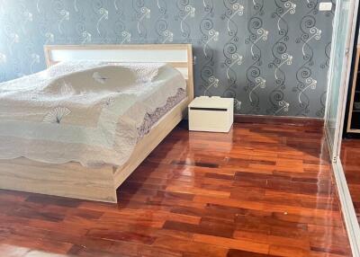 Bedroom with wooden flooring and designed wallpaper