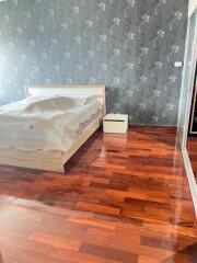 Bedroom with wooden flooring and designed wallpaper