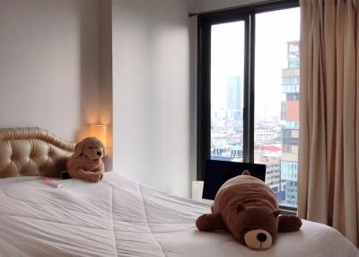 Cozy bedroom with large window and plush toys on the bed