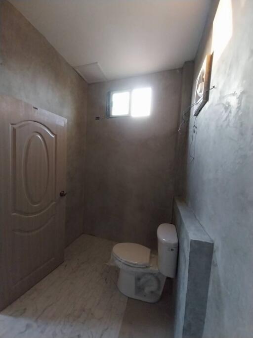 Minimalist bathroom with concrete walls and a small window