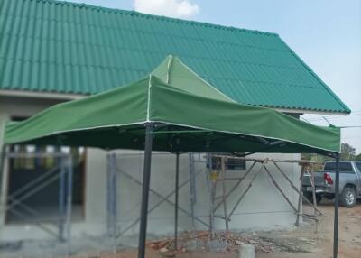 Exterior view of a building under construction with a green roof and canopy