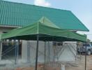 Exterior view of a building under construction with a green roof and canopy