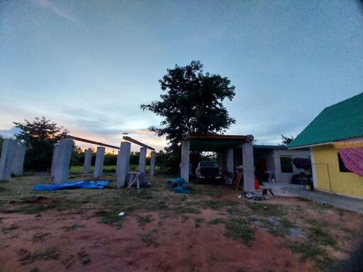 Outdoor view of construction site with an existing structure and tree