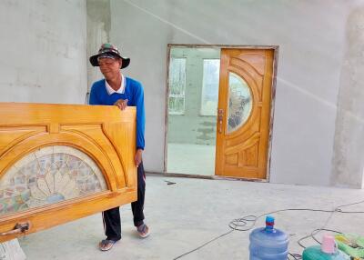 Man working on house construction with detailed wooden door