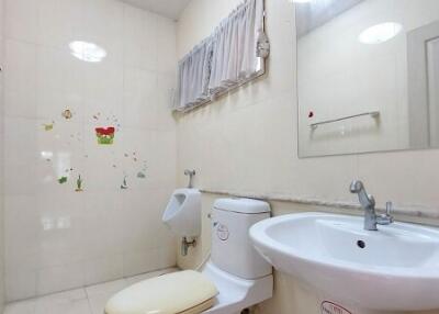 Clean bathroom with toilet, sink, mirror, and wall decorations