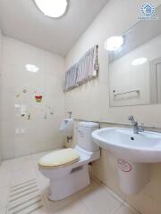 Clean bathroom with toilet, sink, mirror, and wall decorations