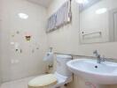 Clean bathroom with toilet, sink, mirror, and wall decorations