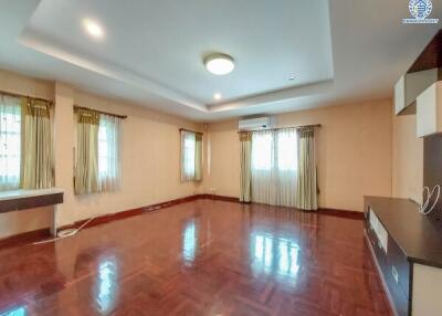 Spacious living room with hardwood floors, large windows, modern lighting, and built-in shelving.