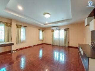 Spacious living room with hardwood floors, large windows, modern lighting, and built-in shelving.